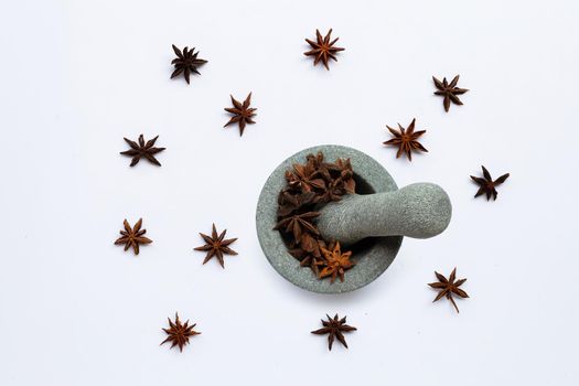 Star anis in  stone mortar with pestle on white background. Top view