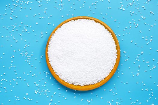 Chemical plant urea fertilizer on pottery plate on blue background. Copy space