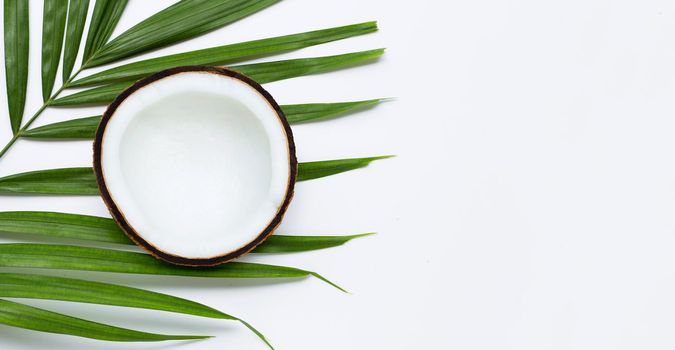 Half coconut on tropical palm leaves on white background. Top view