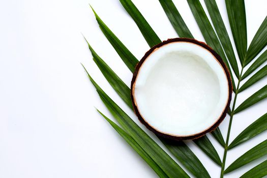 Half coconut on tropical palm leaves on white background. Top view