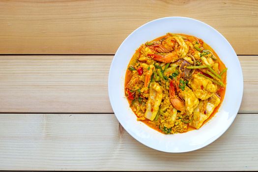 Fried seafood with curry powder on wooden background. Top view
