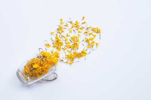 A glass cup with marigold flower petals on white background Flower herbal tea concept.