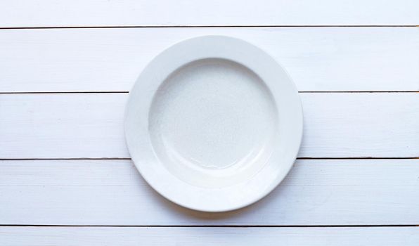 Empty white ceramic plate on white wooden background. Copy space