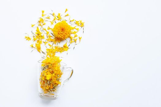 A glass cup with marigold flower petals on white background. Flower herbal tea concept.