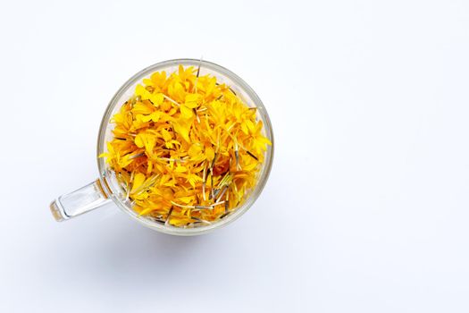 A glass cup with marigold flower petals on white background. Flower herbal tea concept.