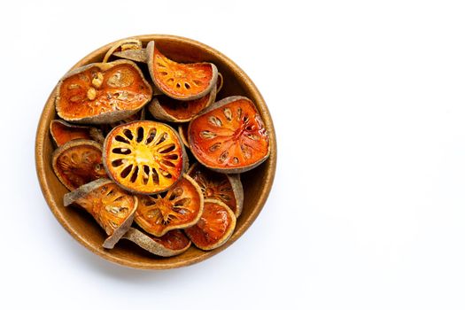 Dried bael fruit in wooden bowl on white background. Top view