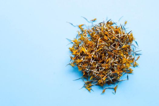 Dried marigold flower petals on blue background. Flower herbal tea concept.