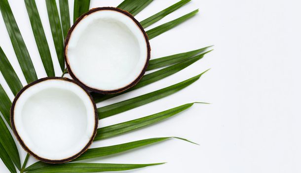 Half coconuts on tropical palm leaves on white background. Top view