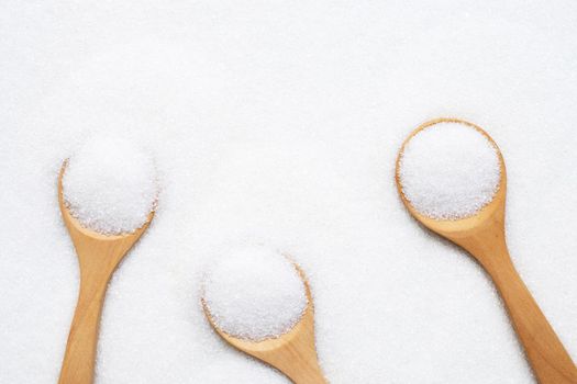 Wooden spoon with white granulated sugar. Top view
