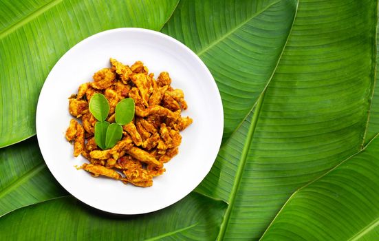Chicken with yellow curry paste on banana leaves background. Thai food