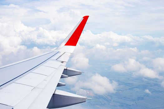 View of land, cloud and wing of airplane from window