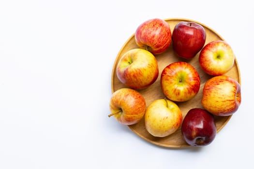 Fresh juicy apples on wooden plate on white background.