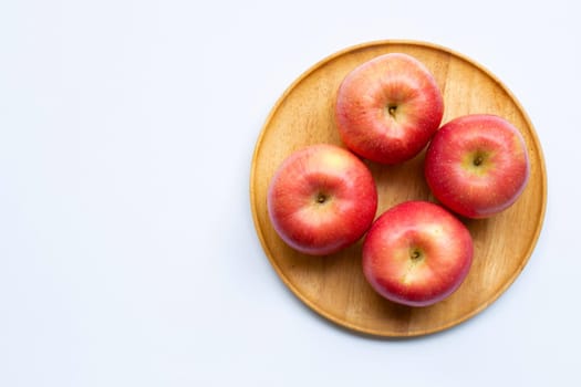 Juicy apples on wooden plate on white background.