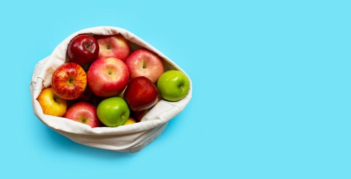 Fresh and juicy apples in cloth bag on blue background. Copy space