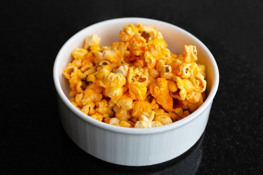 Popcorn in bowl on black background.