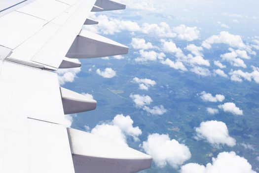 View of land, cloud and wing of airplane from window