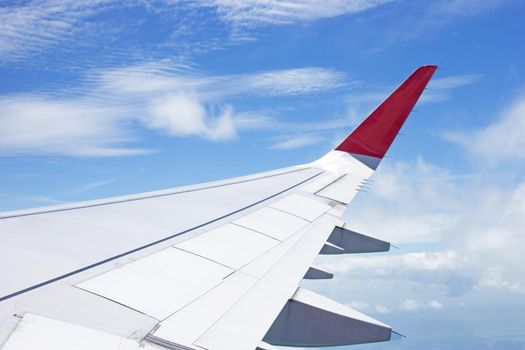View of land, cloud and wing of airplane from window