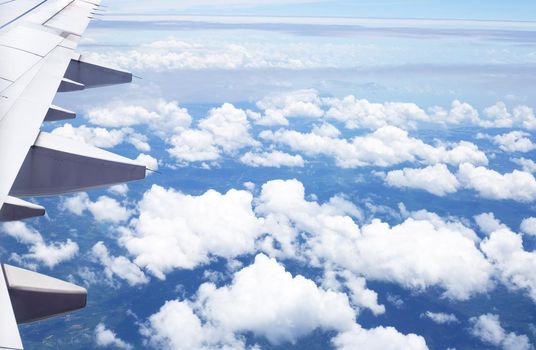 View of land, cloud and wing of airplane from window