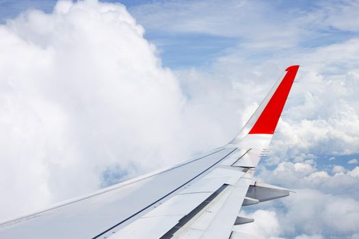 View of sky, cloud and wing of airplane from window