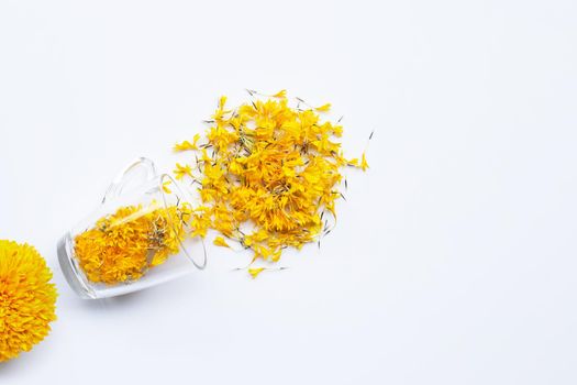 A glass cup with marigold flower petals on white background. Flower herbal tea concept.
