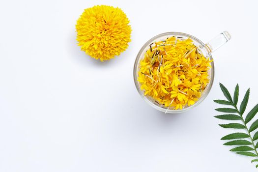 A glass cup with marigold flower petals on white background. Flower herbal tea concept.