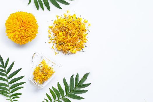 A glass cup with marigold flower petals on white background. Flower herbal tea concept. Copy space