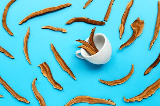 Dried lingzhi mushroom slices with cup on blue background. Top view