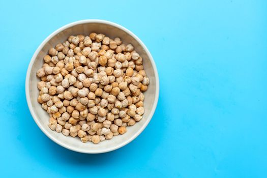Chickpeas in bowl on blue background. Top view