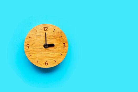 Wooden clock on blue background. Copy space
