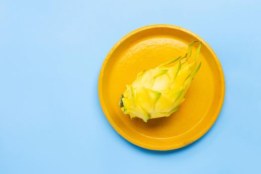 Yellow pitahaya or dragon fruit on yellow plate on blue background. Copy space