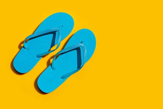 Blue flip flops on yellow background. Enjoy summer holiday concept.