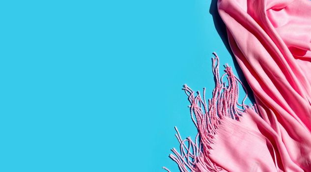 Pink women's shawl on blue background. Copy space