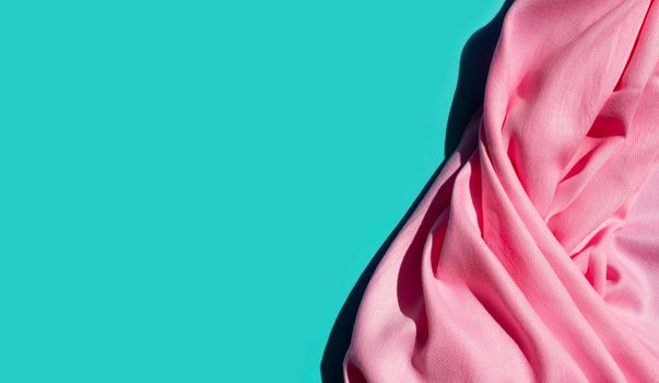 Pink women's shawl on blue background. Copy space