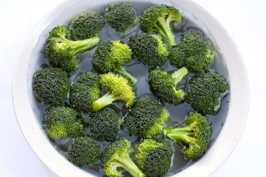 Fresh broccoli soaked in a white bowl of water