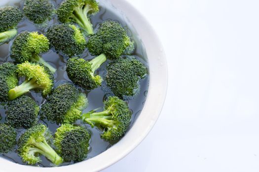 Fresh broccoli soaked in a white bowl of water