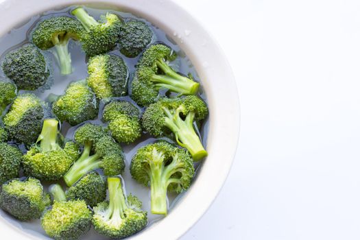 Fresh broccoli soaked in a white bowl of water