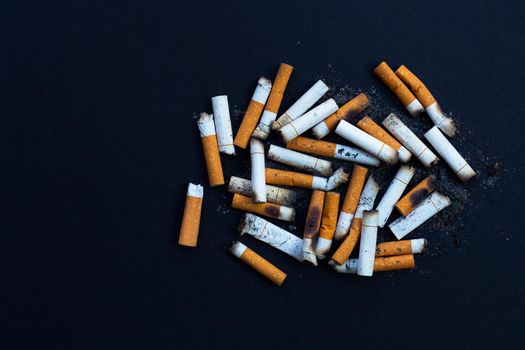 Dirty cigarette buds on black background.