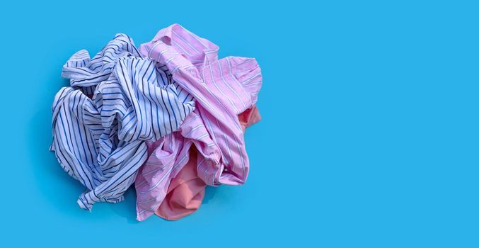 Pile of used clothes on blue background.