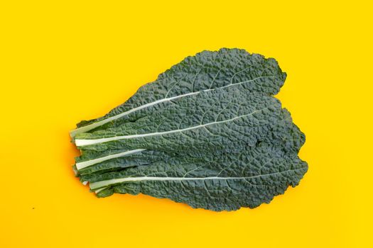 Fresh organic green kale leaves on yellow background.