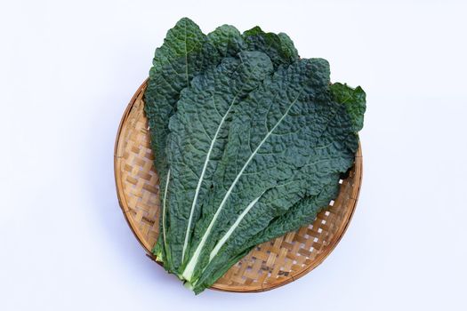Fresh organic green kale leaves in wooden bamboo threshing basket on white background.