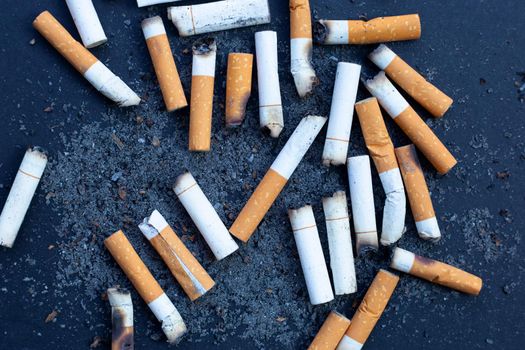 Cigarettes buds with ashtray on dark background.