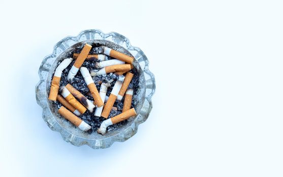 Cigarettes buds in a transparent ashtray on  white background.
