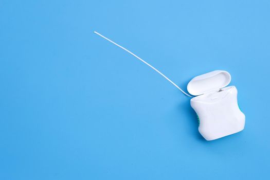 Dental floss on blue background. Copy space