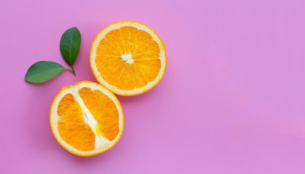High vitamin C, Juicy and sweet. Fresh orange fruit with green leaves on pink background.