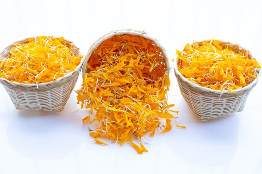 Marigold flower petals in bamboo basket on white background.