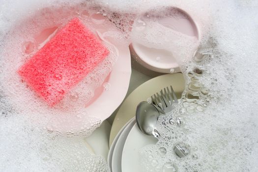 Washing dishes, Close up of utensils soaking in kitchen sink.