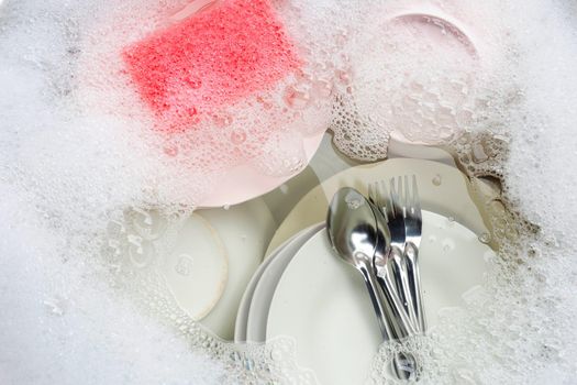 Washing dishes, Close up of utensils soaking in kitchen sink.