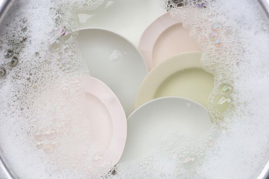 Washing dishes, Close up of utensils soaking in kitchen sink.