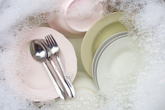 Washing dishes, Close up of utensils soaking in kitchen sink.