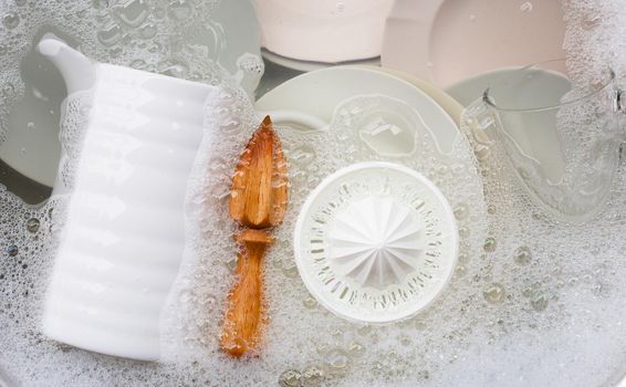 Washing dishes, Close up of utensils soaking in kitchen sink.